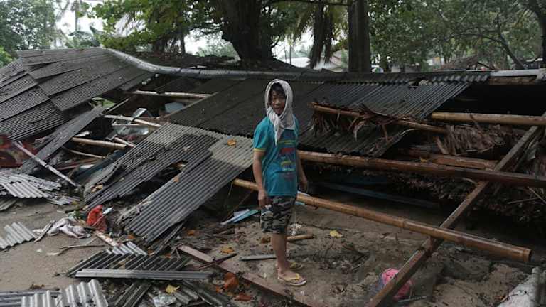 A man inspects his house which was damaged by the tsunami in Carita.