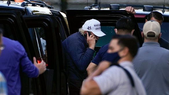 Trump was speaking on a phone as he got out of his vehicle on return to the White House.