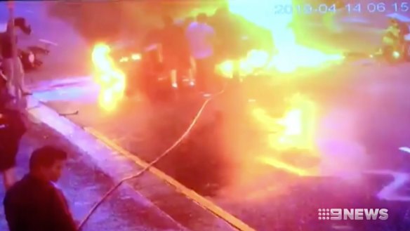 Bystanders work to hose down Charles Williamson's burning Mazda on King Georges Road.