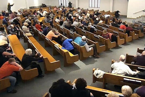 In this still frame from livestreamed video provided by police, churchgoers take cover while a congregant armed with a handgun (top left) engages a man who opened fire (near top centre just right of windows) during a service at West Freeway Church of Christ in White Settlement, Texas. 