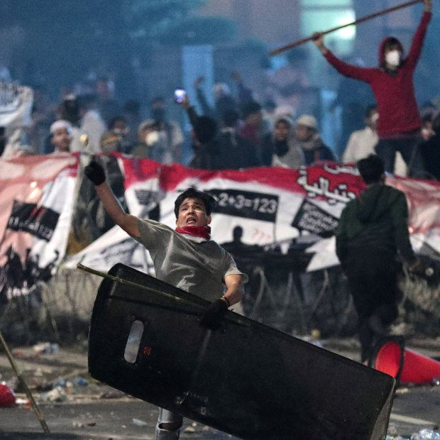 A supporter of Indonesian presidential candidate Prabowo Subianto throws a rock at riot police.