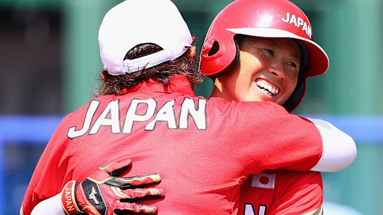 Yamato Fujita of Japan gets a hug from head coach Reika Utsugi after hitting a home run in the fourth inning against Australia during the Tokyo Games.