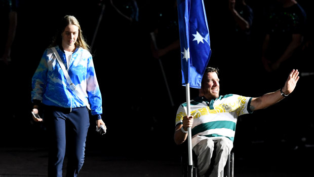 Kurt Fearnley carries the Australian flag into Carrara Stadium.