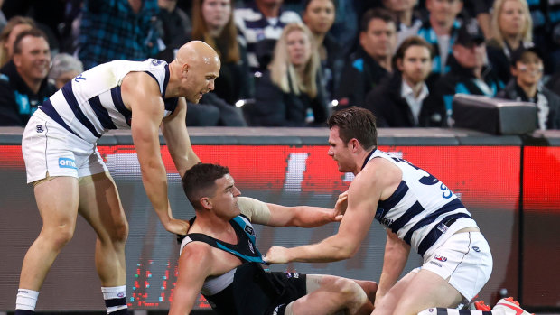 Port's Tom Rockliff is brought down by Patrick Dangerfield and Gary Ablett.