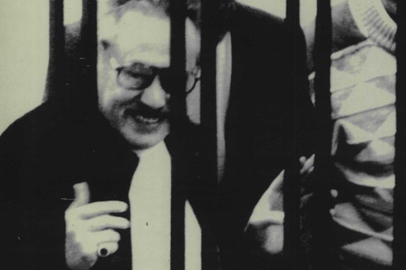 Luciano Leggio (left), the reputed “boss of bosses” of Italian Cosa Nostra, smiles from behind the bars during the mafia trials in Sicily in 1986. 