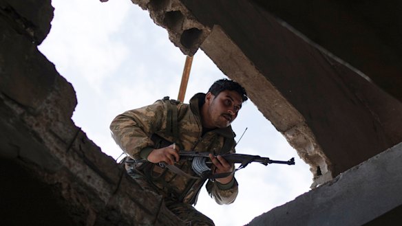 A US-backed Syrian Democratic Forces (SDF) fighter enters a building as fight against Islamic State militants continues in the village of Baghouz, Syria, on Saturday.