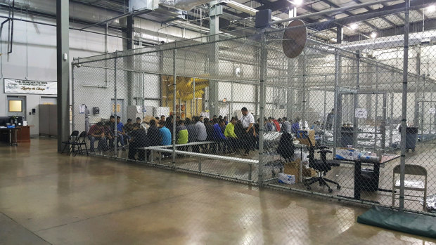People taken into custody related to cases of illegal entry into the US sit in one of the cages at a facility in McAllen, Texas. 