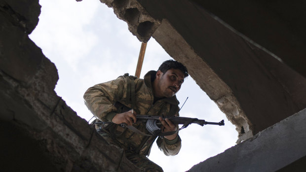 A US-backed Syrian Democratic Forces (SDF) fighter enters a building as fight against Islamic State militants continues in the village of Baghouz, Syria, on Saturday.