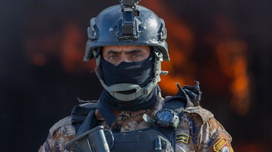 An Iraqi soldier stands guard in front of smoke rising from a fire set by pro-Iranian militiamen and their supporters in the US embassy compound in Baghdad.