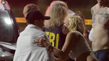 People comfort each other as they stand near the scene in Thousand Oaks, California.