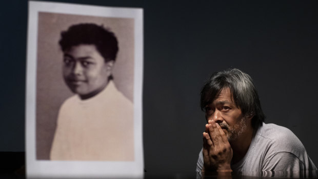 Mark Apuron, 45, sits beside a photo of himself when he was 15 years old, the age when he says he was raped by his uncle, former Archbishop Anthony Apuron, in Guam.