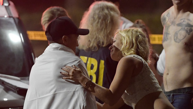 People comfort each other as they stand near the scene in Thousand Oaks, California.