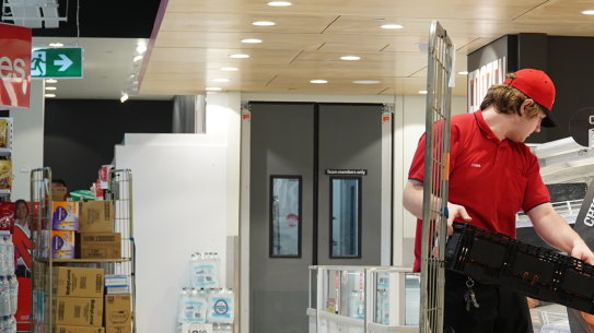 Restocking an empty fridge at a Coles supermarket.