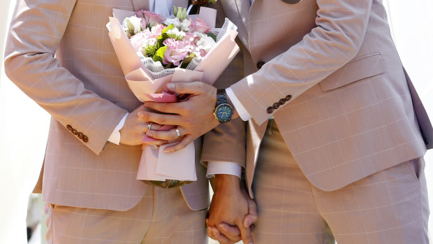 A married couple holds a bouquet during a pro same-sex marriage party.