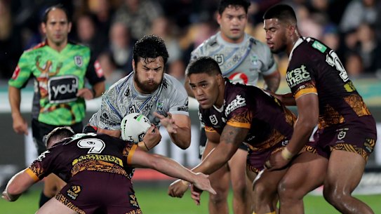 The wall: The Brisbane defence crowds out the Warriors' Peta Hiku.
