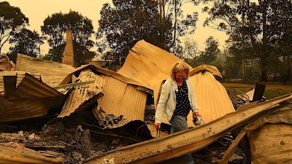Averil Berryman walks through the ruins of her business in Mogo’s Main Street that was destroyed by the fire that swept through the town.