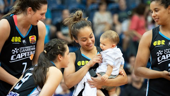 The Canberra Capitals' Lauren Scherf, Abby Cubillo, and Hannah Young share the moment with Leilani Mitchell's son Kash after winning the 2018-19 WNBL championship.