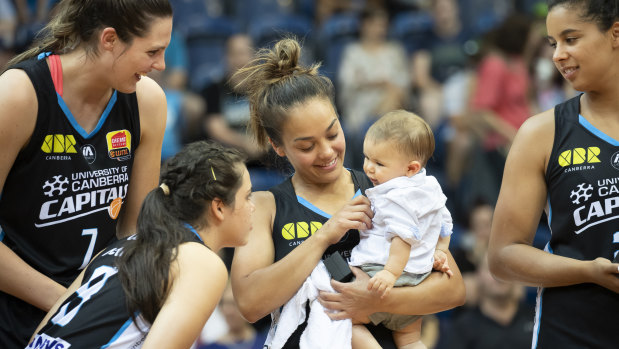 The Canberra Capitals' Lauren Scherf, Abby Cubillo, and Hannah Young share the moment with Leilani Mitchell's son Kash after winning the 2018-19 WNBL championship.