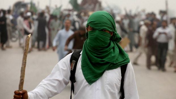 A supporter of a radical Islamic group stands guard as protesters block a main highway to condemn a Supreme Court decision that acquitted Asia Bibi, a Christian woman accused of blasphemy, in Peshawar, Pakistan.