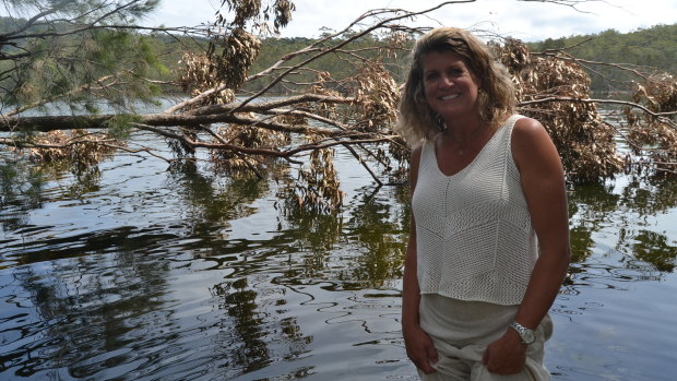 Lake Conjola resident Kristen Bird by a fallen tree which she said collapsed into the water from flooding.