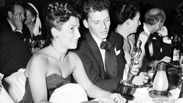 Frank Sinatra steals a glance at his Oscar which he won for his performance in the film "The house I live in," as his wife Nancy looks on in 1946.