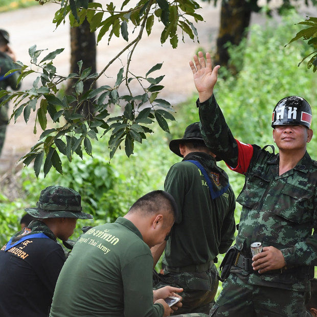 A Thai military policeman holds up five fingers to indicate the number of people rescued from the cave. 