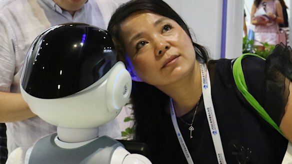A woman listens to what a robot responds to her at the World Robot Conference.