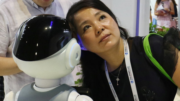 A woman listens to what a robot responds to her at the World Robot Conference.