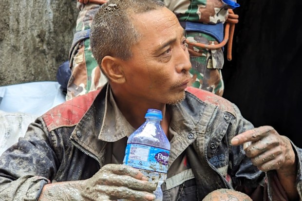 Kurtarılan bir Çinli, Nepal'in Rasuwa bölgesindeki Trishuli-3A hidroelektrik projesinde askerler tarafından kurtarıldıktan sonra su içiyor.