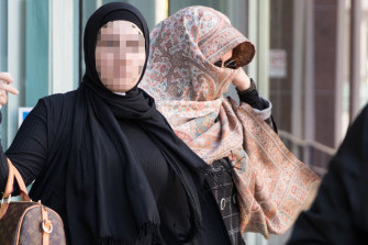 Lubna Al-Hashimy, right, covers her face with a scarf after being arrested over the alleged fraud. She is pictured leaving Bankstown police station with a supporter who has not been charged with any offences.