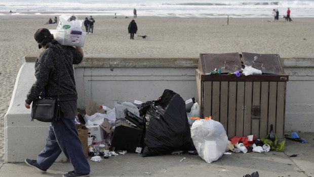 A woman walks past rubbish piled next to a garbage bin at Ocean Beach in San Francisco last week.