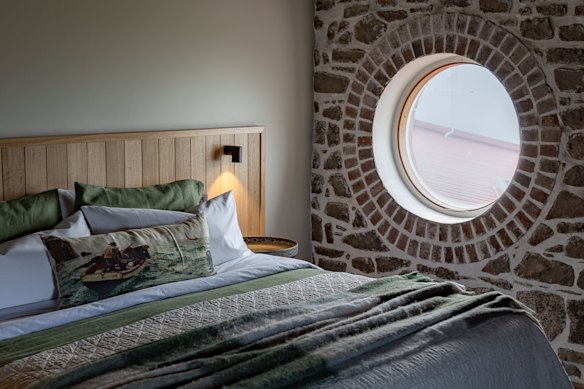 The bedroom’s porthole and timber-lined ceiling establish a maritime mood.