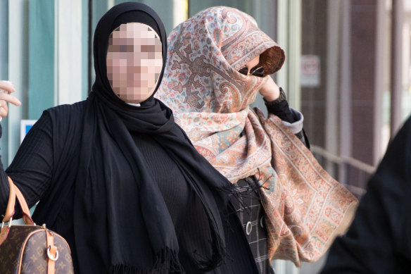 Lubna Al-Hashimy, right, covers her face with a scarf after being arrested over the alleged fraud. She is pictured leaving Bankstown police station with a supporter who has not been charged with any offences.