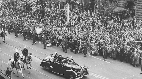 Large crowds watch the Queen and Prince Philip as they parade along Swanston Street.