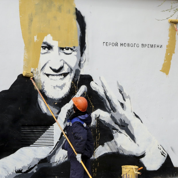 A municipal worker in St Petersburg paints over a mural of imprisoned opposition leader Alexei Navalny, in April.