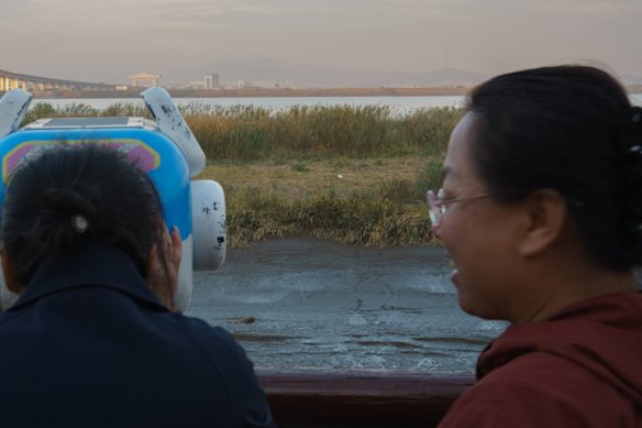 Chinese tourists use binoculars to get a closer look at the New Yalu River Bride and the North Korean city of Sinuiju.