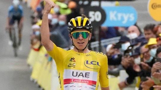 Tadej Pogacar, wearing the overall leader’s yellow jersey, celebrates as he crosses the finish line. 