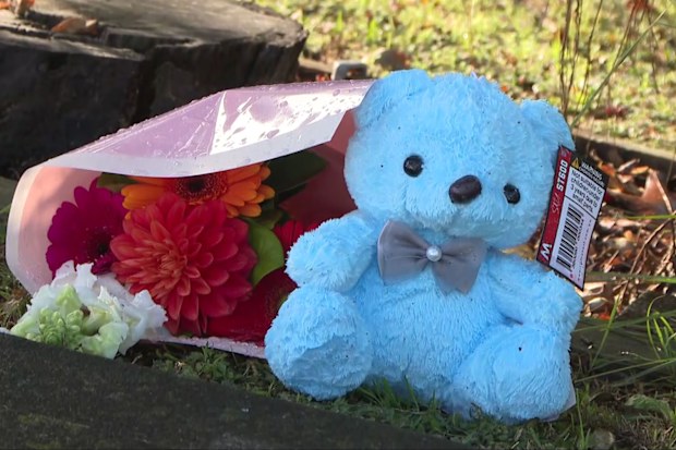 A teddy bear and flowers left by members of the community.