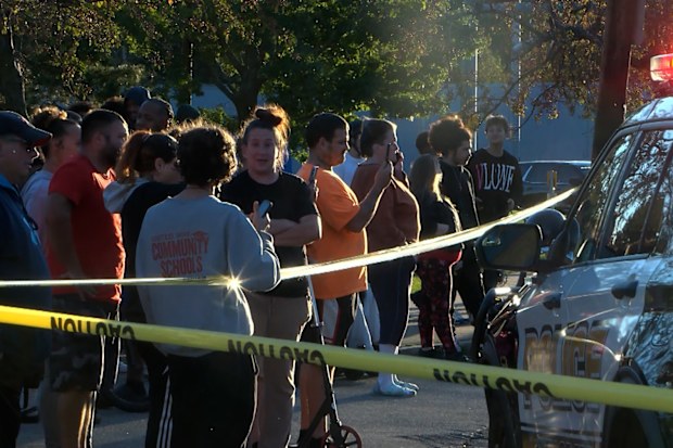 Bystanders gather outside the scene of the shooting in Erie on Friday.