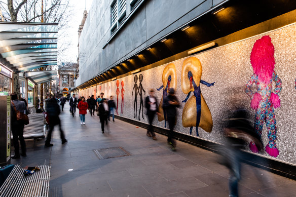 Melburnians walk past temporary hoardings by the Huxleys. 