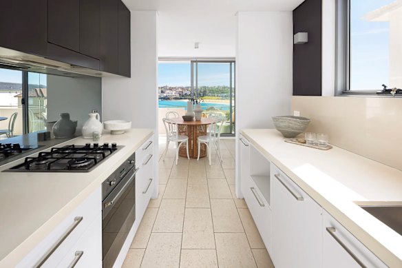 The apartment for sale has neutral interiors, a stone-topped kitchen, tiled floors and a full-width balcony. 