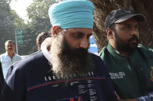 Policemen escort Rajwinder Singh, 38, in 2022.