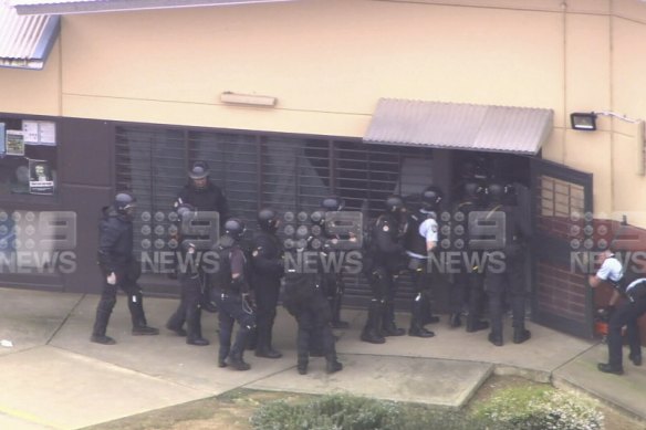 Special Operations Group officers storm the building at Acacia Prison on Wednesday afternoon. 