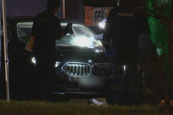 Police inspect a BMW with a bullet hole through the windscreen in Taylors Hill.