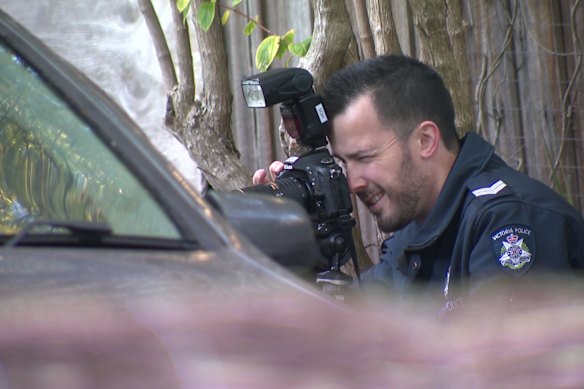 Police photographing the bullet holes in Douglas Lee’s car after last month’s shooting.