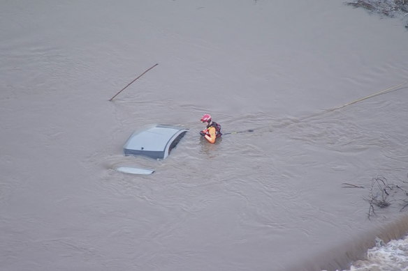 Helicopter footage shows an SES volunteer checking a car that was almost entirely submerged on the Menangle Bridge.