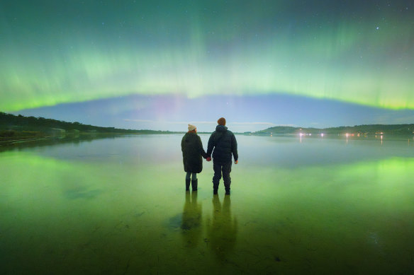 Sky’s the limit: this photo of two people watching the aurora australis light up a southern Tasmanian beach at about 5am on Saturday was taken on a digital camera.