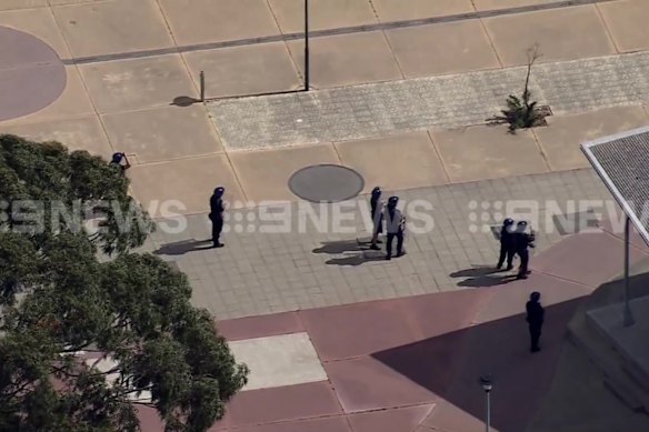 Prison officers in riot gear watch from the ground as youths climb the roof of Banksia Hill on Monday.