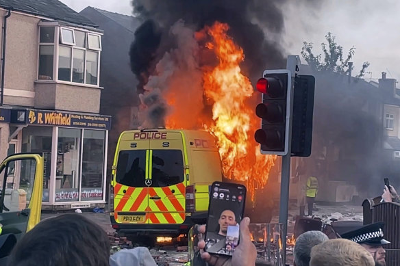 A police van burns as an unruly crowd clashes with police earlier in the week.