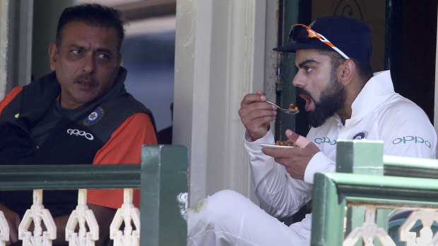Not ideal practice: Virhat Kohli eats while taking a break from a long day in the field.